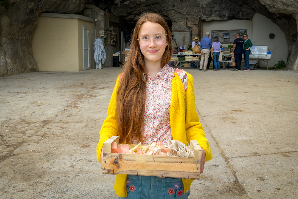 Our daughter at the Orbec Mushroom Farm with a crate full with champignons